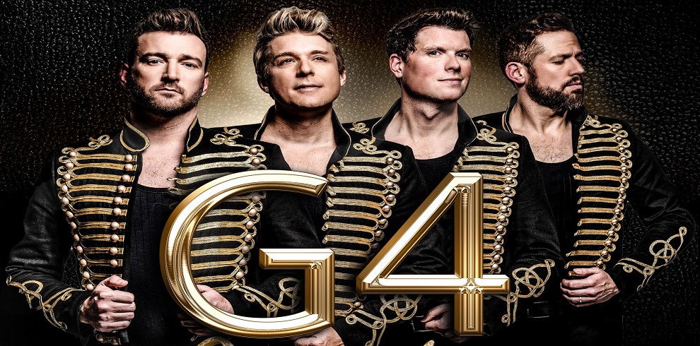 A picture of the four cast members of G4. The text G4 is shown in gold font in front of the band.