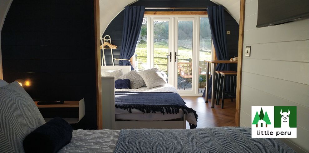 An image of a bedroom with 2 beds with sun shining through the patio doors.