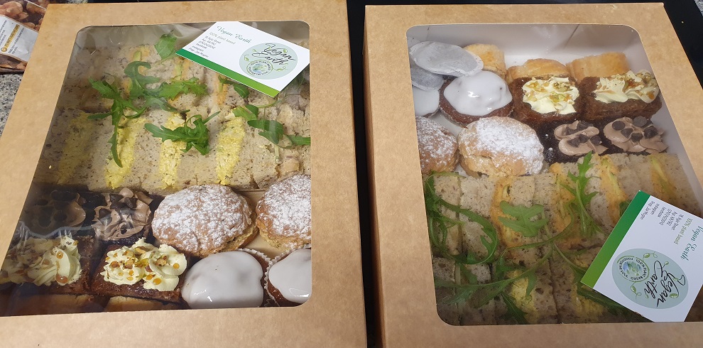 A pciture of a selection of cakes and ssandwiches in a take away box.