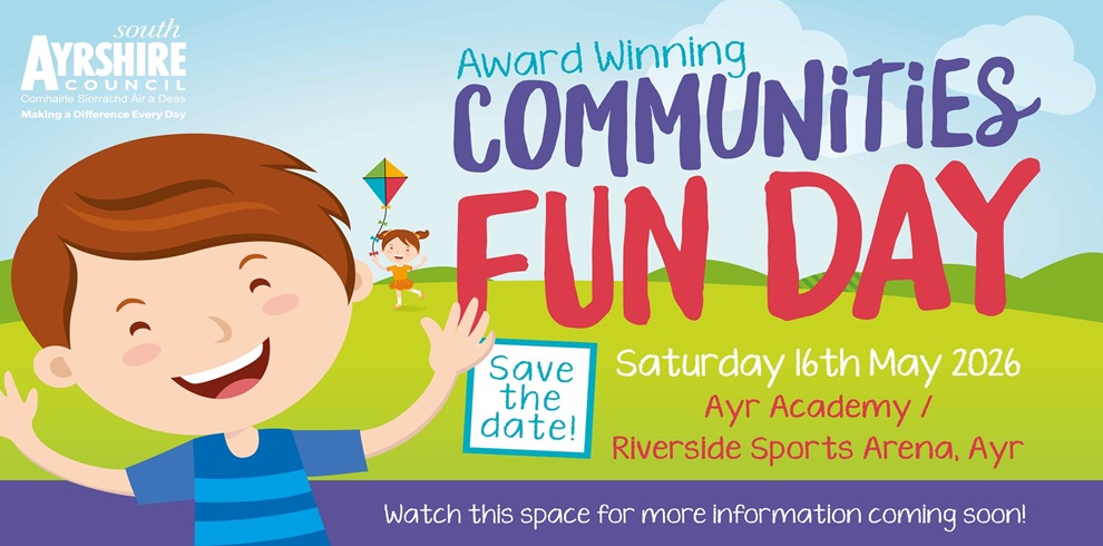 A colourful illustrated poster for “Award Winning Communities Fun Day.” A smiling cartoon child waves in the foreground, with another child flying a kite in a green park under a blue sky. Text reads: “Save the date – Saturday 16th May 2026, Ayr Academy / Riverside Sports Arena, Ayr.” The South Ayrshire Council logo appears in the top left, with a note at the bottom saying, “Watch this space for more information coming soon.