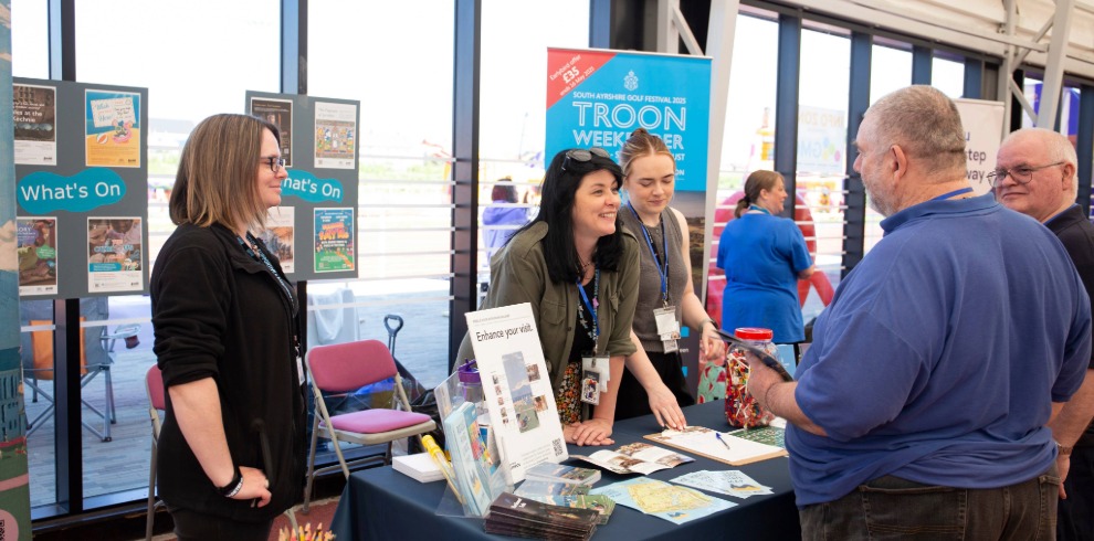 People engaging at a stall table at an event.