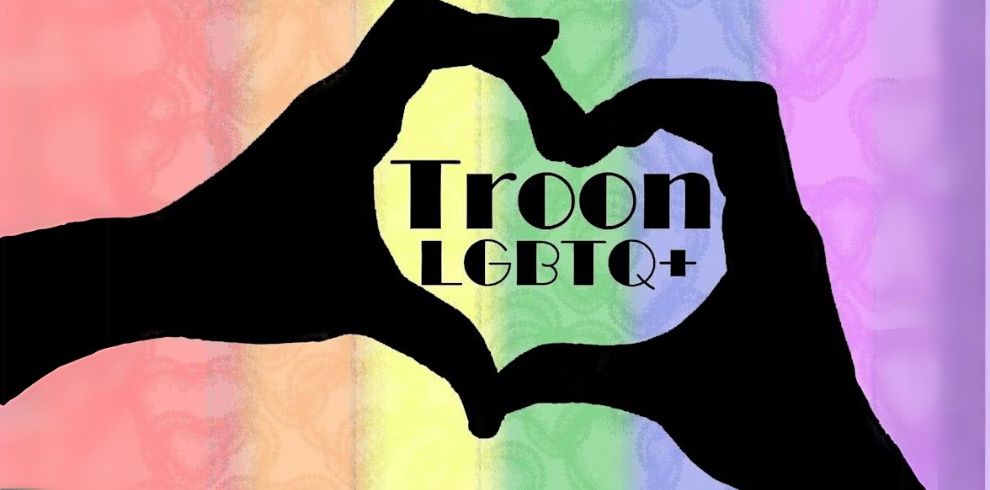 A graphic image of silhouettes of two hands forming a heart shape over a rainbow-colored background. Inside the heart shape, bold black text reads 'Troon LGBTQ+'. The background features soft gradients of pink, red, orange, yellow, green, blue, and purple, symbolizing the Pride flag.