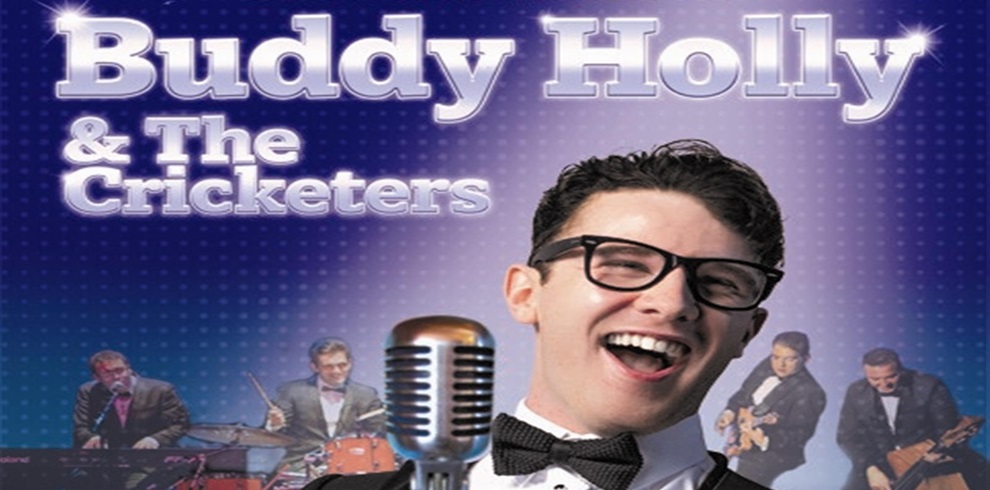 A promotional poster featuring the text 'Buddy Holly & The Cricketers' in large, bold letters at the top. Below the text, four musicians with blurred faces are shown playing instruments, including a guitar and drums. In the foreground, a close-up of a man wearing glasses and a bow tie stands behind an old-fashioned microphone, also with his face blurred. The background features a blue gradient with small dots, giving the image a retro feel.