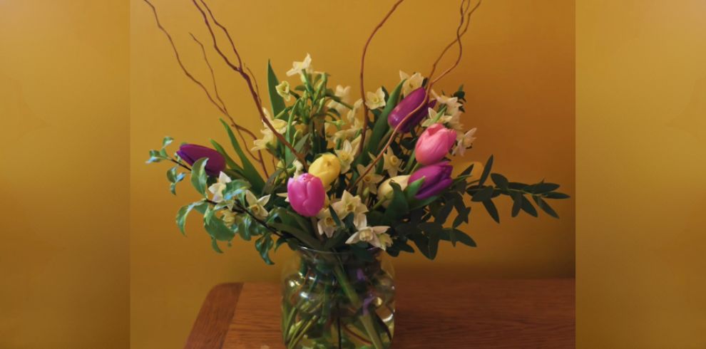An image of a floral display in a vase on a table.