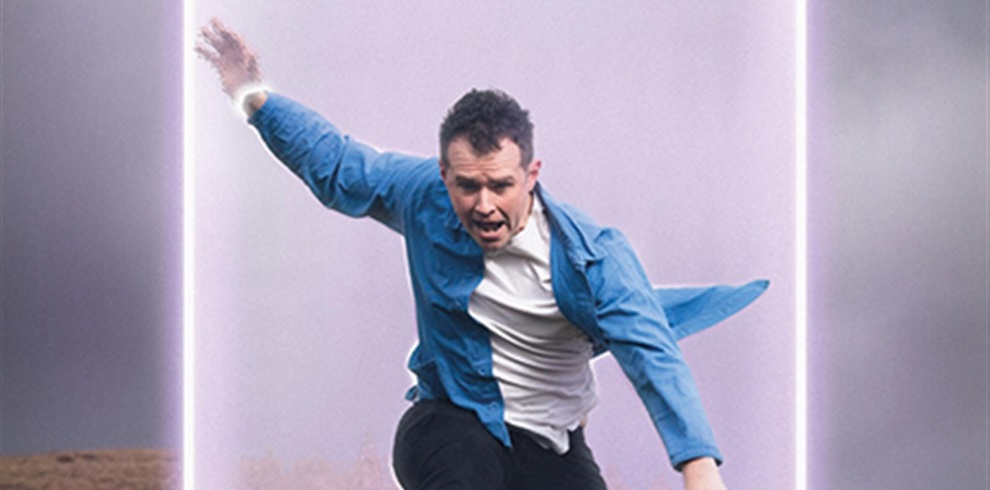 A person with a blurred face is captured in mid-motion, either running or jumping. They are wearing a blue jacket over a white shirt and black pants. Behind them is a glowing rectangular frame with bright light edges, giving the scene a futuristic or surreal appearance.