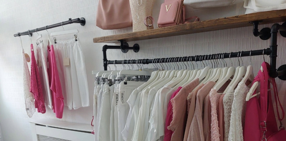 Clothing boutique interior wih rails of clothes.