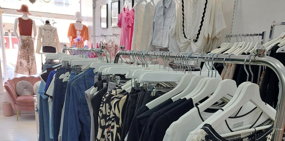 Clothing boutique interior wih rails of clothes.