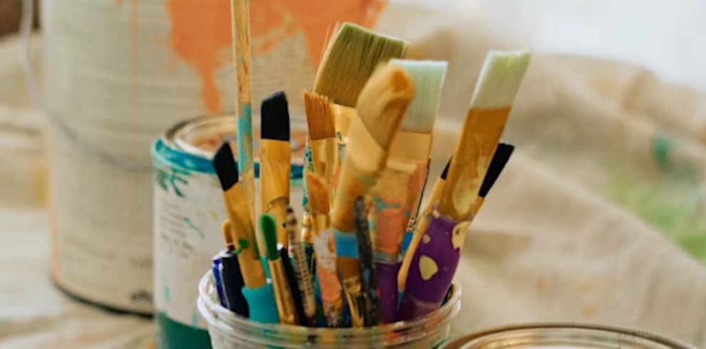 A photo of paintbrushes in a can placed on a table.