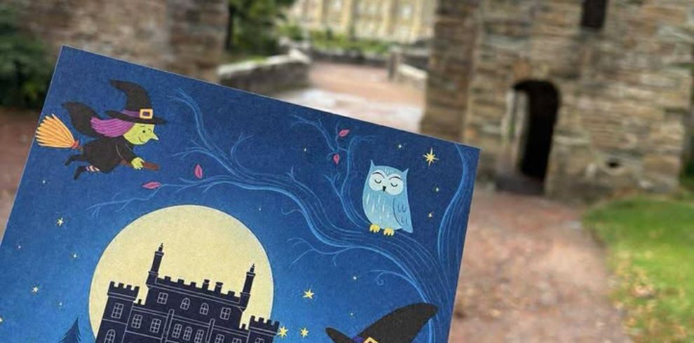 Hand holding a spooky flyer while facing castle gates