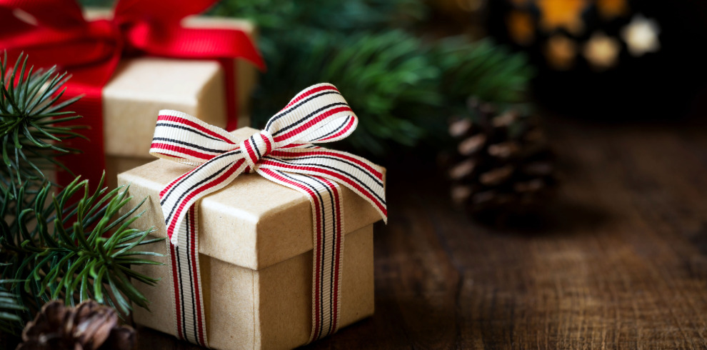 Beautifully wrapped presents with bows next to a Christmas tree.