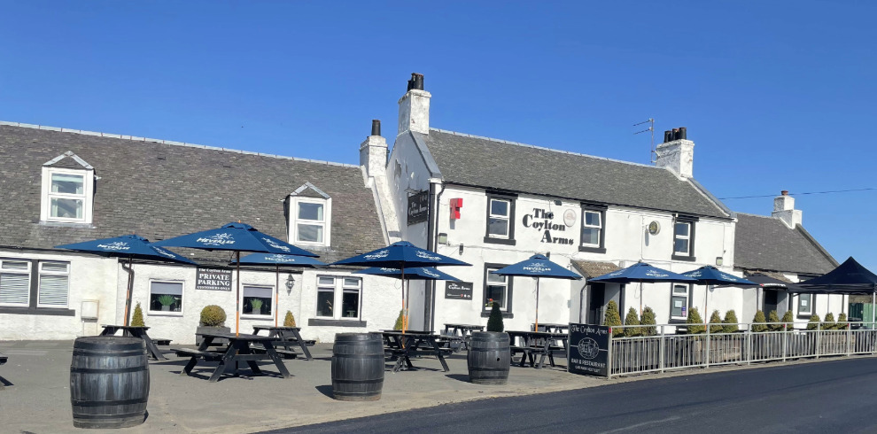 Exterior of a large white buidling with patio furniture.