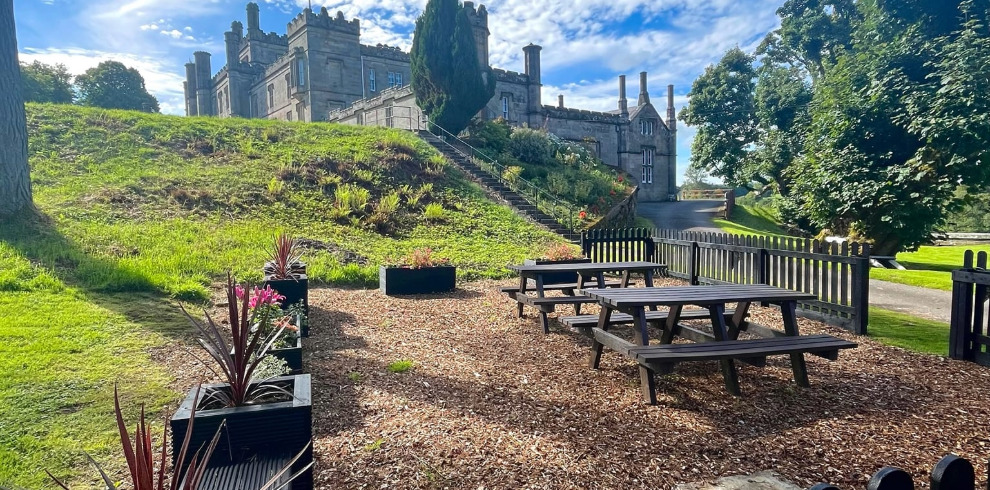 Picnic benches and flowers with castle in the distance.