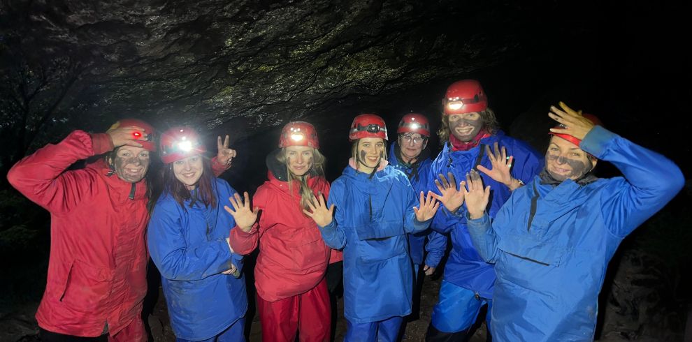 Seven women posing for the camera in a cave.