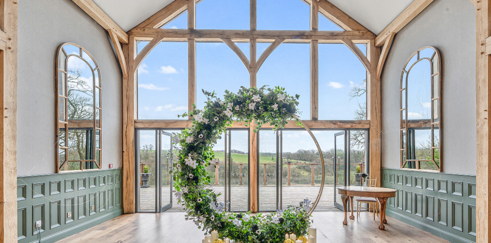 Glass window looking out to countryside. Arched flower arrangement.