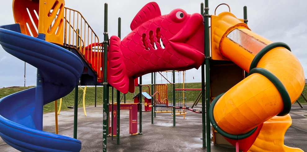 Giant red fish outdoor play equipment at play park beside the beach.
