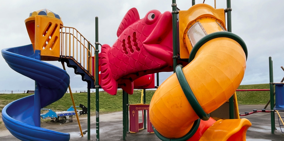 Giant red fish outdoor play equipment at play park beside the beach.
