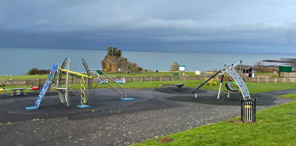 Outdoor play equipment at play park with coastal views.