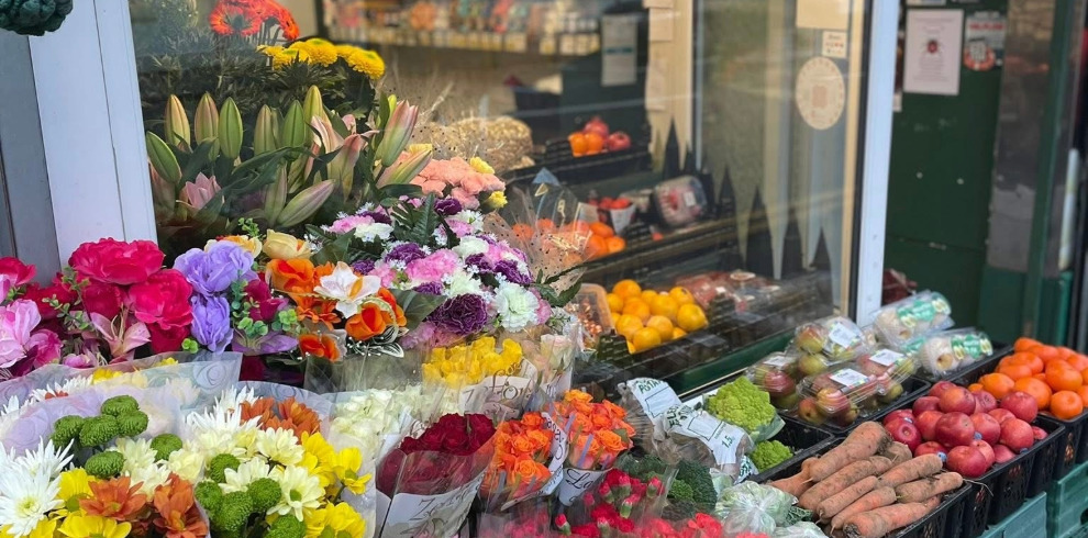 Shop front with flowers and fresh fruit on display.