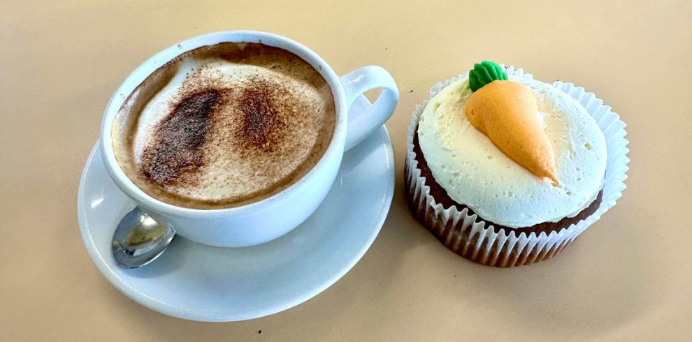An image of a cappucino and a carrot cake muffin.