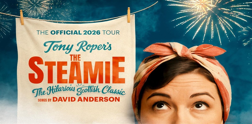 Promotional image for Tony Roper’s The Steamie 2026 official tour. A laundry sheet hangs on a washing line with the show title printed on it in bold red and blue lettering. Fireworks light up the night sky in the background. To the right, the top of a person’s head is visible, wearing a red‑and‑white headscarf tied in a bow.