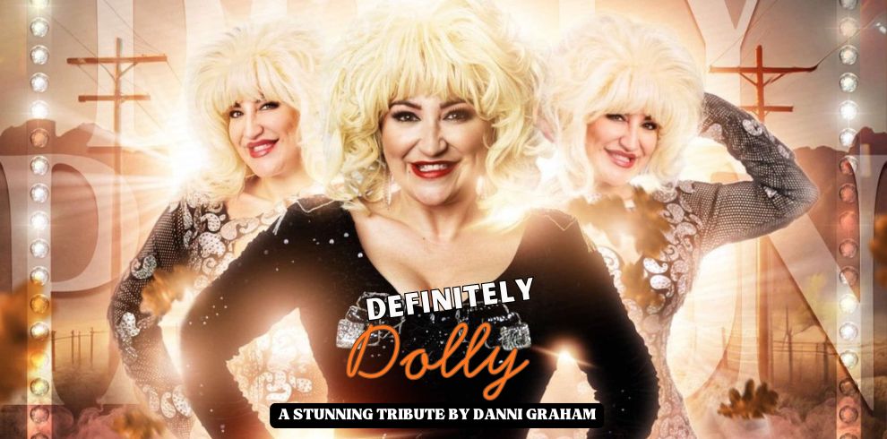 A promotional banner image featuring three performers wearing bright blonde wigs and sparkling, embellished outfits. The central figure stands in front with hands on hips, while two additional figures pose behind on either side. The background shows a glowing stage-like setting with warm lights, spotlights, and decorative elements. Text on the poster reads “DEFINITELY Dolly” in a bold stylised font, followed by “A STUNNING TRIBUTE BY DANNI GRAHAM.”