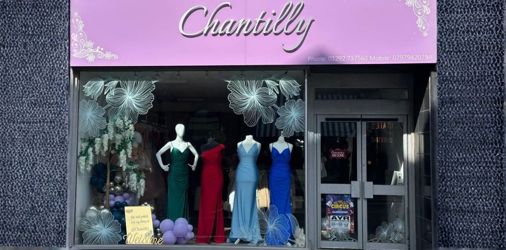 A shop window showcasing various prom dresses.