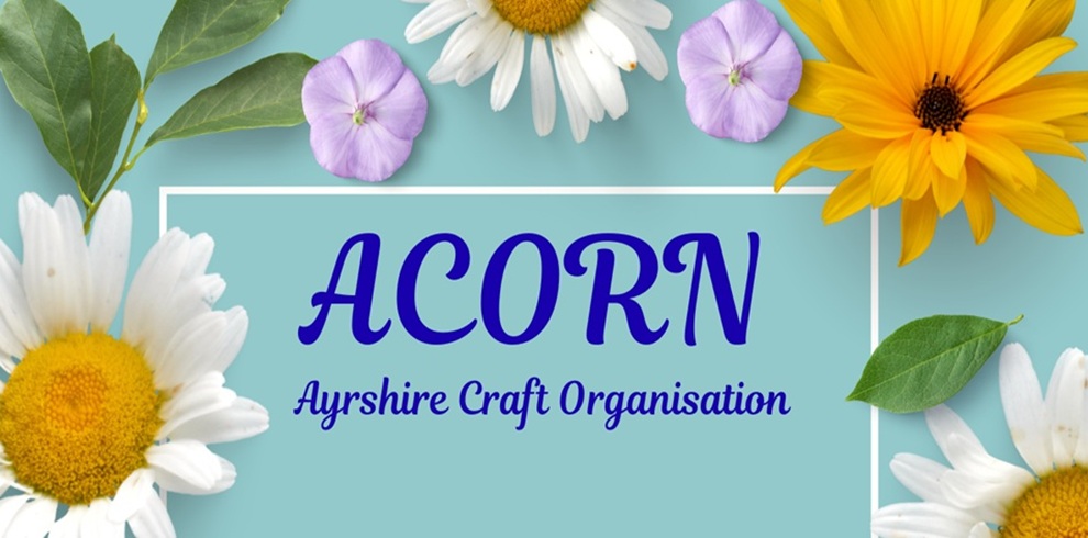 Banner with the text “ACORN – Ayrshire Craft Organisation” in blue lettering on a teal background, surrounded by white daisies, yellow flowers, small purple flowers, and green leaves arranged around a white rectangular border.