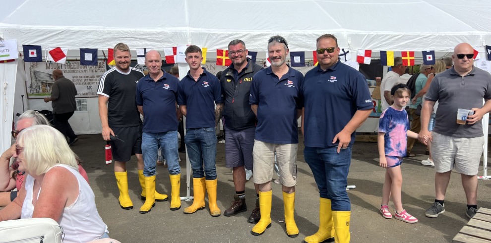 Group of men at a festival wearing yellow wellington boots.