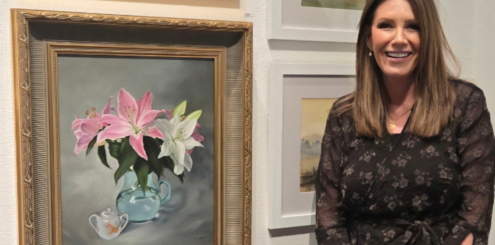 West Coast Canvas Exhibition and Workshops 3 Woman standing next to a painting of flowers.