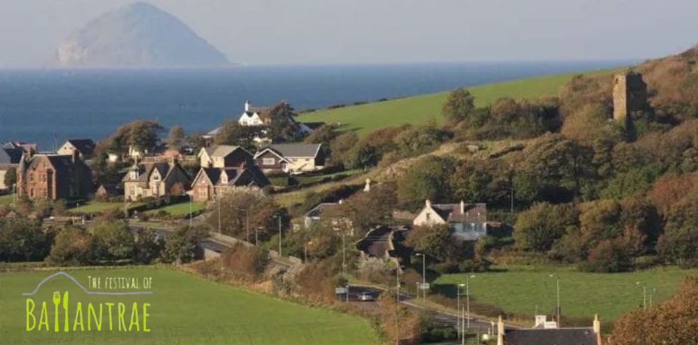 A scenic image of Ballantrae village with Ailsa Craig visible in the background. There is a logo that says 'The Festival of Ballantrae'.