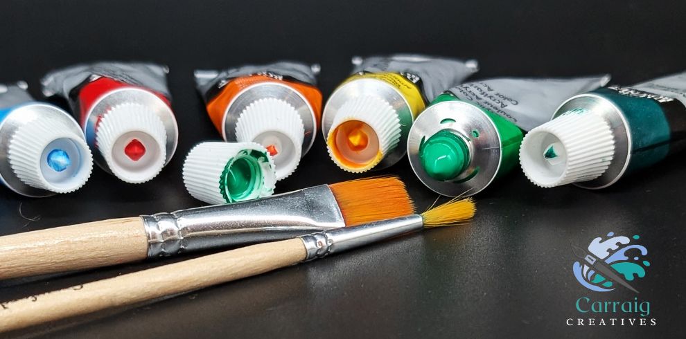 An image of various colours of paint tubes and paintbrushes with the 'Carraig Creatives' logo on the bottom right-hand corner.