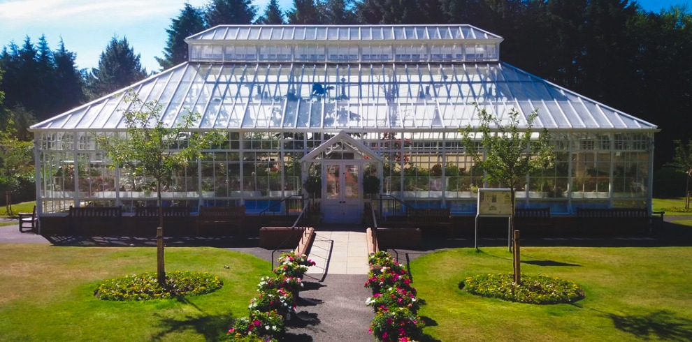 Large glass conservatory surrounded by beautiful gardens.