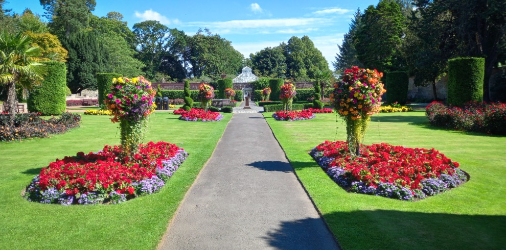Path lined with stunning flower beds and manicured lawns.