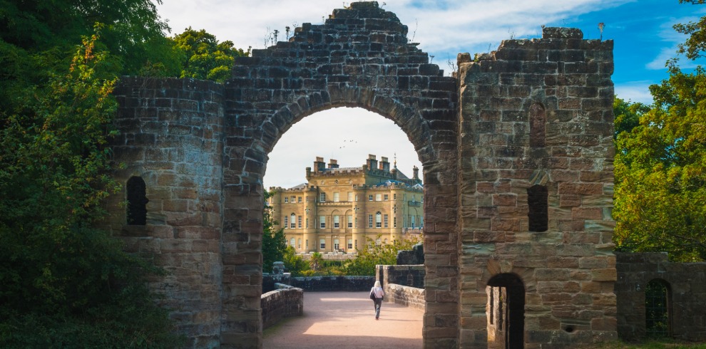 Stone ruined archway to a stunning large castle.