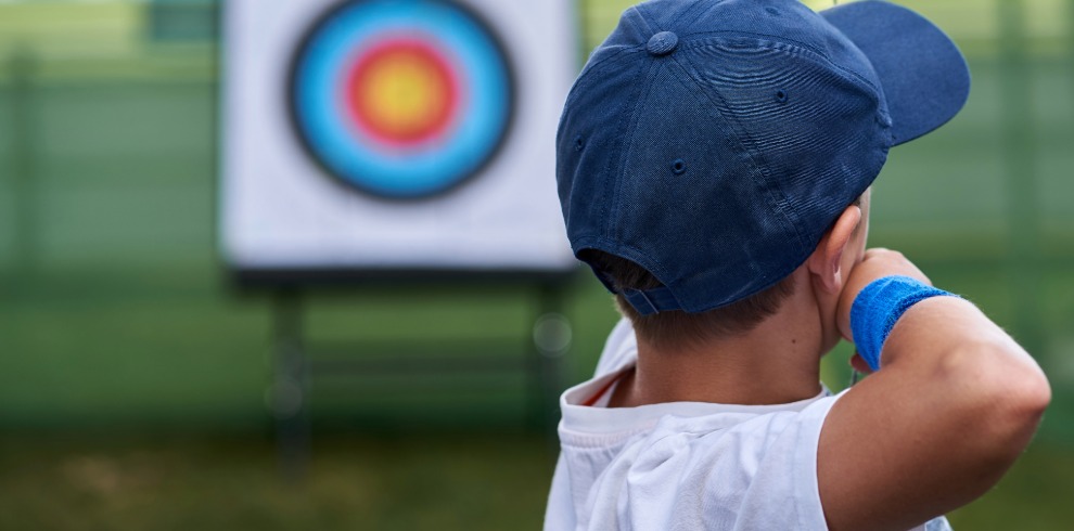 Young boy aiming at archery target.
