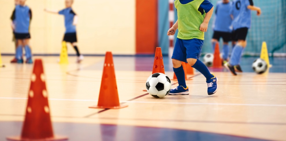 Young children playing football indoors.
