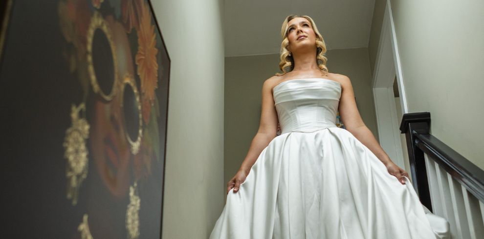 An image of a bride posing at the top of a staircase.