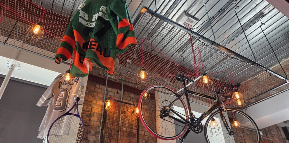 Sport shirts and bike hanging from a ceiling.
