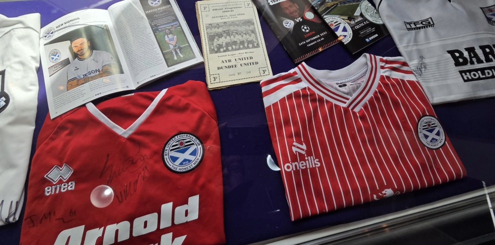 Football shirts in a display cabinet.