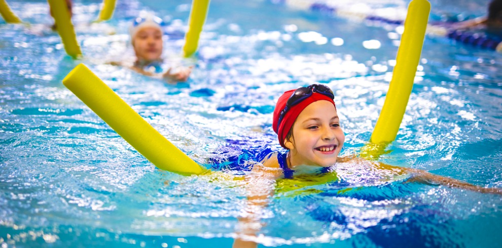 Young girl using float noodle to help swim.