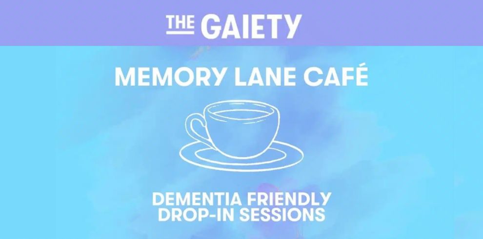 Promotional graphic for The Gaiety Memory Lane Café. The image has a blue and purple watercolor-style background. At the top, the text reads “THE GAIETY” in white. In the center, large white text reads “MEMORY LANE CAFÉ” above a simple white line drawing of a coffee cup on a saucer. At the bottom, white text reads “DEMENTIA FRIENDLY DROP-IN SESSIONS.” The overall design is clean and calming, using light blue, turquoise, and lavender tones.