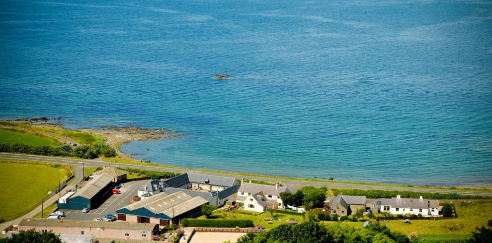 An aerial view of Woodland Bay Hotel and the sea on a bright and sunny day.
