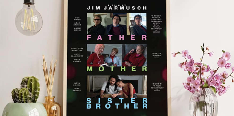 Father Mother Sister Brother 8 A framed film poster displayed on a light-coloured interior wall between a hanging light bulb, potted cacti and a vase of pink flowers. The poster has a black background and features nine still images arranged in three horizontal rows, each showing groups of people seated or standing together indoors. Large coloured text across the rows reads “FATHER,” “MOTHER,” and “SISTER BROTHER.” The director's name, “JIM JARMUSCH,” appears at the top in white lettering, with cast names listed along the sides. The overall design uses a grid layout with pastel-coloured typography and candid-looking character portraits.