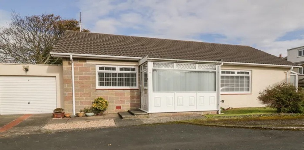 Front exterior of Honesty Cottage, a single-storey detached bungalow with an enclosed porch, private garage, and driveway, situated in a quiet residential cul-de-sac.