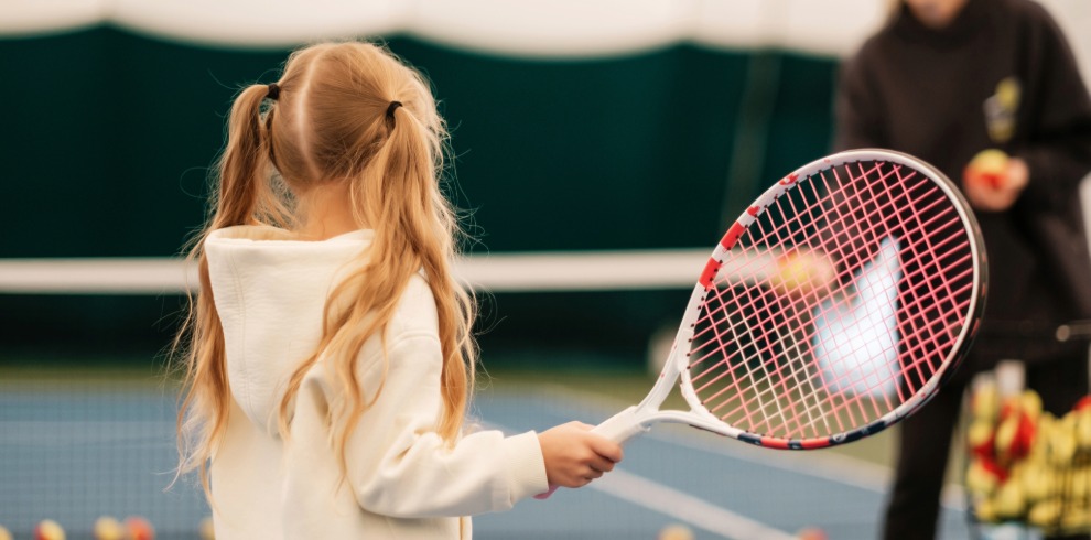 Young girl playing tennis on an outside court.