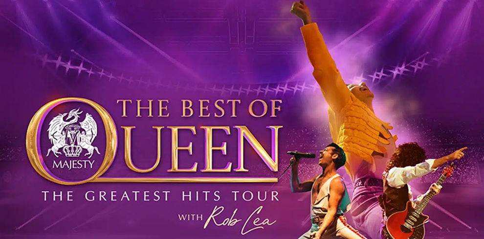 Promotional poster for a Queen tribute show set against a purple concert-stage background with dramatic spotlights. Large gold text in the center reads “The Best of Queen,” alongside a circular crest logo featuring the word “Majesty.” Smaller text below reads “The Greatest Hits Tour” and “with Rob Lea.” The image includes three performers in stage costumes: one large figure in the background with an arm raised, and two musicians in the foreground, one singing into a microphone and another playing an electric guitar. The design uses vibrant purple and gold tones, creating a theatrical arena-concert atmosphere.