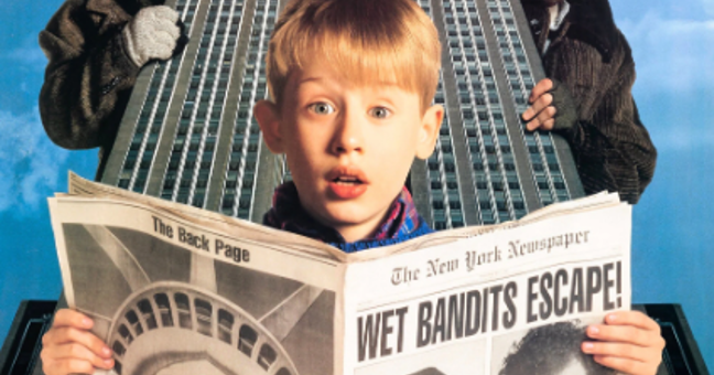 Promotional image for Home Alone 2: Lost in New York. A child stands in the foreground holding an open newspaper with the headline “WET BANDITS ESCAPE!” Behind the child is a tall New York skyscraper viewed from below, creating a dramatic backdrop. Two partially visible figures appear on either side of the building, peering into the frame. The image uses bright colours and a collage-style composition that highlights the New York setting and the film's comedic adventure theme.