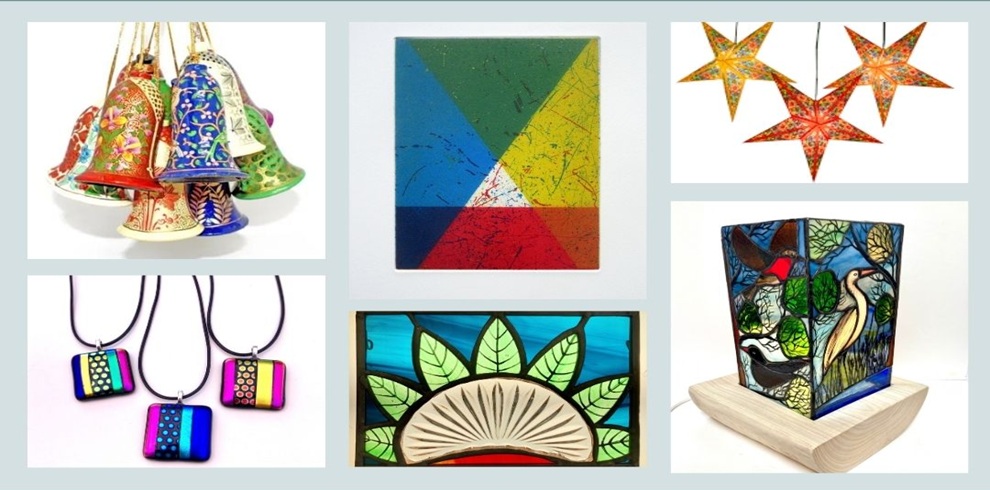 Collage of handcrafted artwork and gifts featured at the Annual Carrick Road Christmas Show. Images include colourful hand-painted ceramic bells, a bright geometric abstract artwork with blue, green, yellow and red triangular sections, illuminated star-shaped paper lanterns in warm orange and red patterns, colourful fused-glass pendant necklaces, a stained-glass panel with leaf motifs in blue and green tones, and a decorative stained-glass lamp depicting birds and nature scenes. The items are displayed against a light grey background, showcasing a range of handmade arts, crafts and festive decorations.