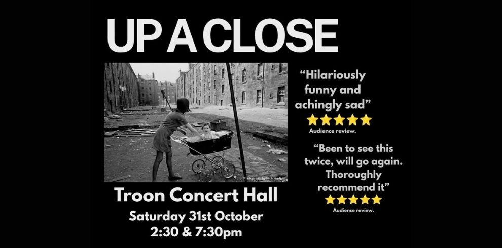 Promotional image for 'Up A Close' at Troon Concert Hall. The design features a black background with the title “UP A CLOSE” in large white lettering at the top. Beneath the title is a black-and-white photograph of a child pushing a pram along a rundown street lined with tenement buildings. On the right-hand side are five-star audience review quotes reading “Hilariously funny and achingly sad” and “Been to see this twice, will go again. Thoroughly recommend it.” Event details below the photograph state: “Troon Concert Hall, Saturday 31st October, 2:30 & 7:30pm.”