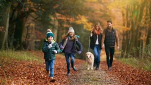 Family walking on a path with their dog through woodland.